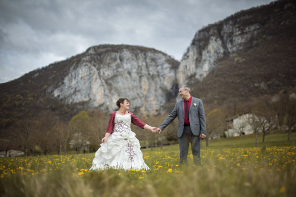 les mariés se tiennent la main devant la montagne